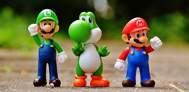Luigi, Yoshi and Mario Action Figures Stood in a Line on a Path with Greenery in the Background