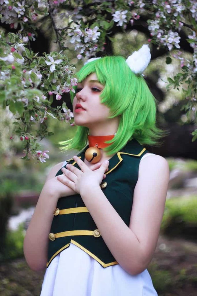A Kawaii Girl Smelling a Flower in a Dress Up Cosplay Costume Wearing a Green Wig