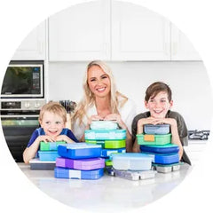 Adventure Snacks Founder Tracey Batt in her kitchen with her two boys holding lunchboxes