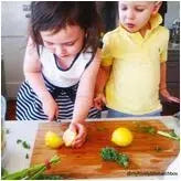 Two children cutting a lemon on a chopping board
