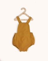 Noble Sun Suit in Turmeric color hanging from a kids hangar