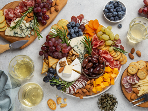 Multiple boards with cheese, fruit, and charcuterie