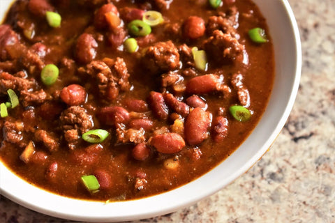 Bowl of bison meat chili with red beans and green onion.