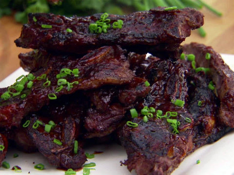 Plate of bison spare ribs with orange honey chipotle bbq sauce.