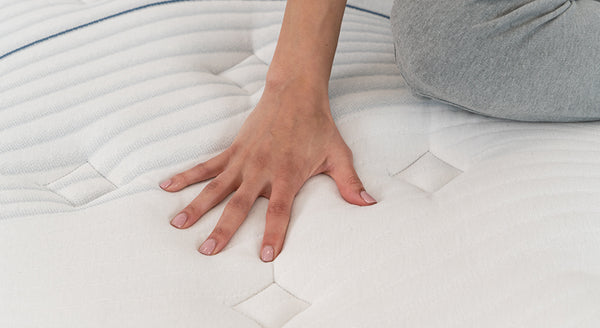 Hand touching a mattress