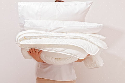 A man holding fresh sheets and pillows