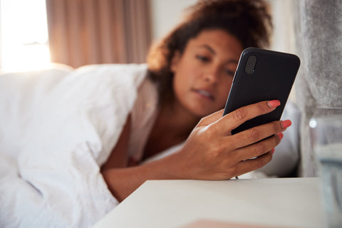 Woman checking her phone in bed