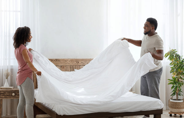 Two people making the bed