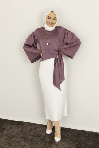 a woman wearing a lilac satin blouse with a white skirt and a hijab