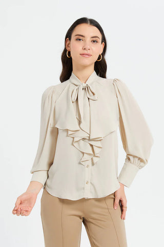 a woman wearing a beige blouse with tie