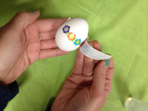 Applying temporary tattoo to Easter egg