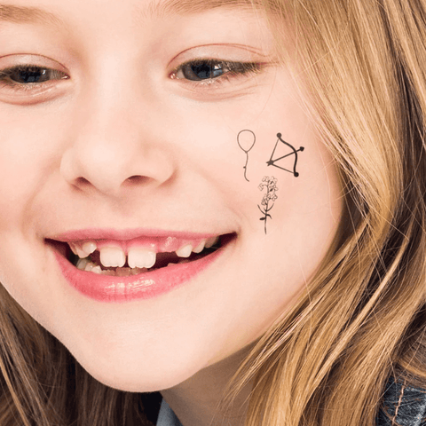 young girl with tiny temporary tattoos on cheek