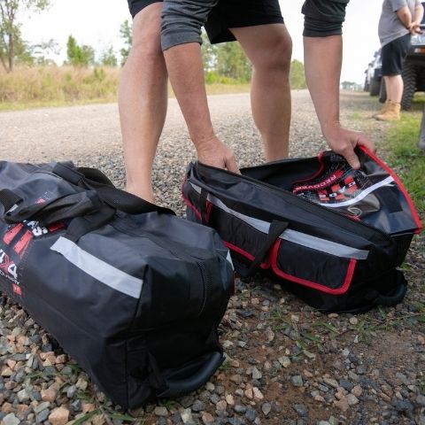 Person opening equipment bag filled with 4x4 recovery gear