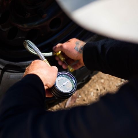 Man using tire deflator to drop air pressure in tyre 