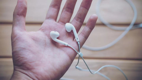 A Hand Holding a Pair of Wired Earbuds