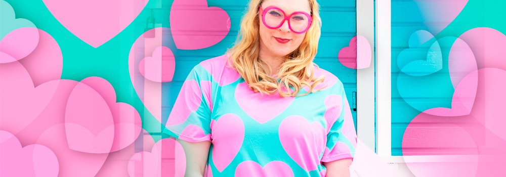 A smiling woman in pink glasses surrounded by pink hearts, wearing ELLIE LOVE pink mint t-shirt dress by SHALMIAK.
