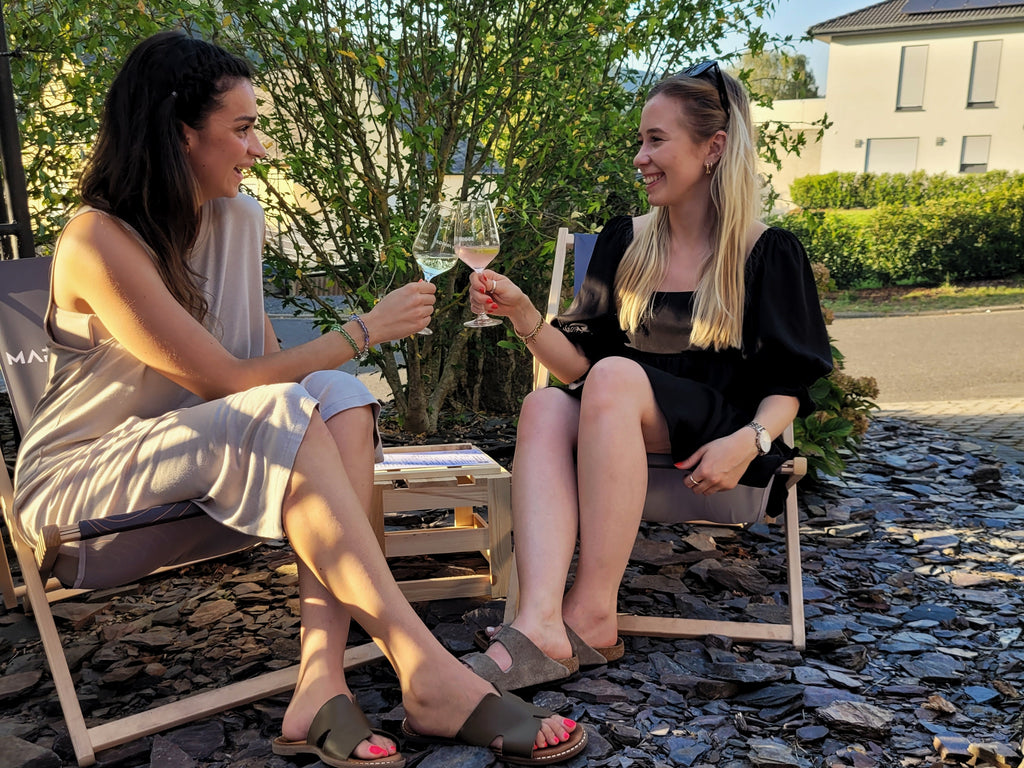 Zwei junge Frauen stoßen auf dem Weingut Maring Prigge mit einem Glas Wein an.