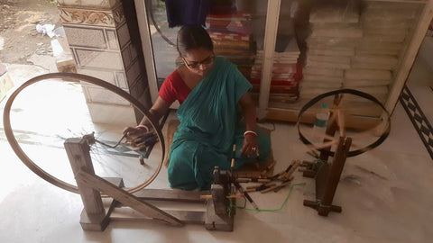 Women making thread from cotton fibers to be put on loom