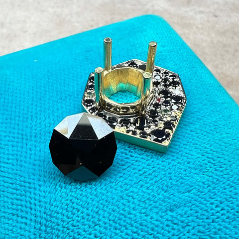 Black Spinel center stone with geometric round cut. Top of one of a kind ring next to center stone. Top is pre-set with mostly black sapphire melees