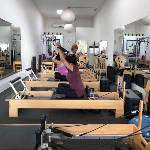 Woman doing Pilates on a Pilates Reformer with Good Citizen Pilates Reformer Loops.