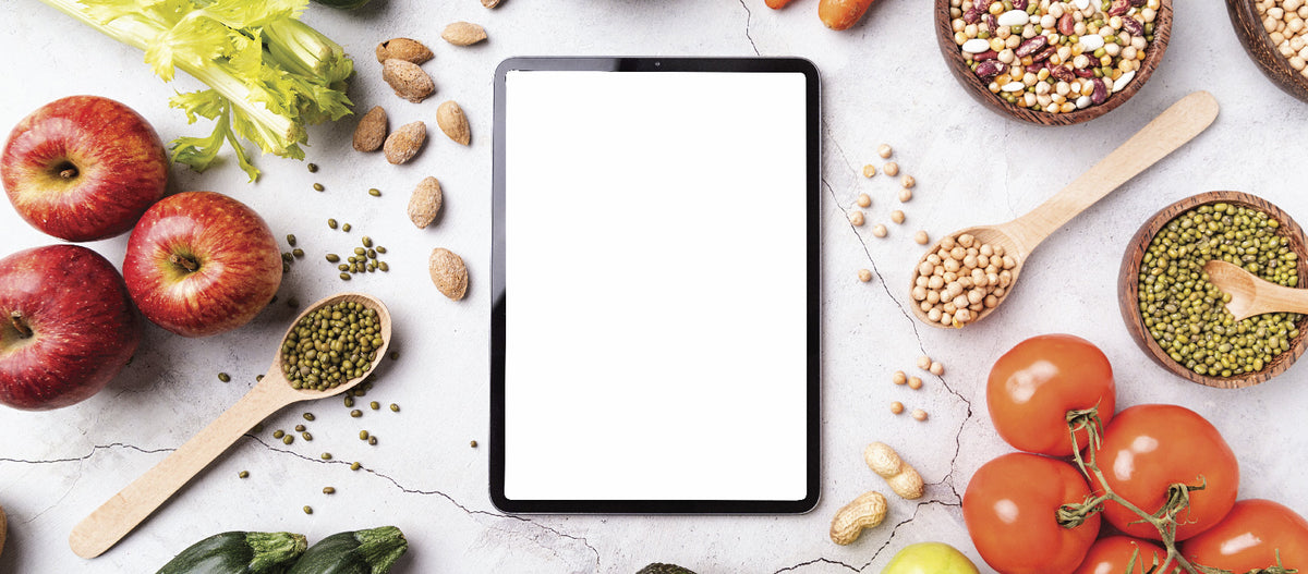 A tablet for meal planning with health foods on the side