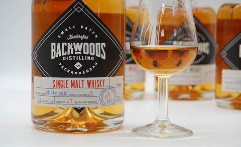 Bottle of Backwoods single malt, with a glass of whisky beside it