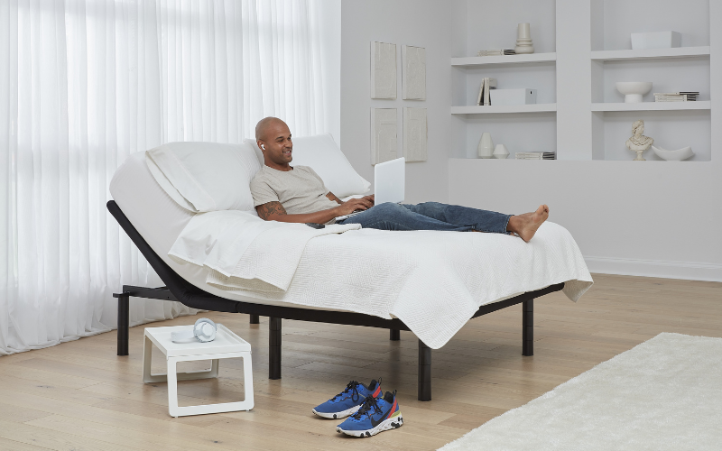 Man in a queen bed while on his laptop