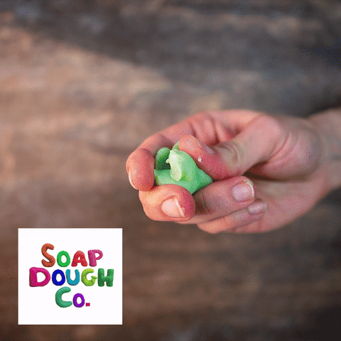 Gif of hand squeezing bright green soap dough.
