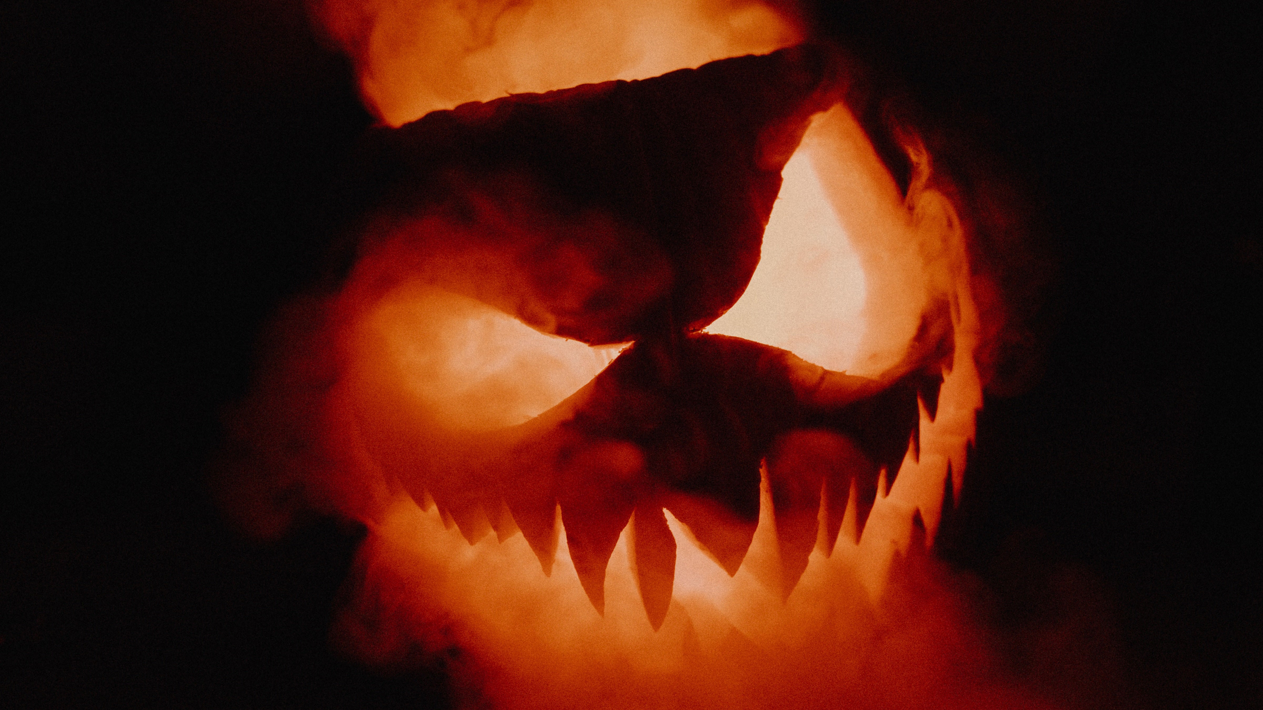 Scary looking jack-o-lantern lit up with smoke coming out of it