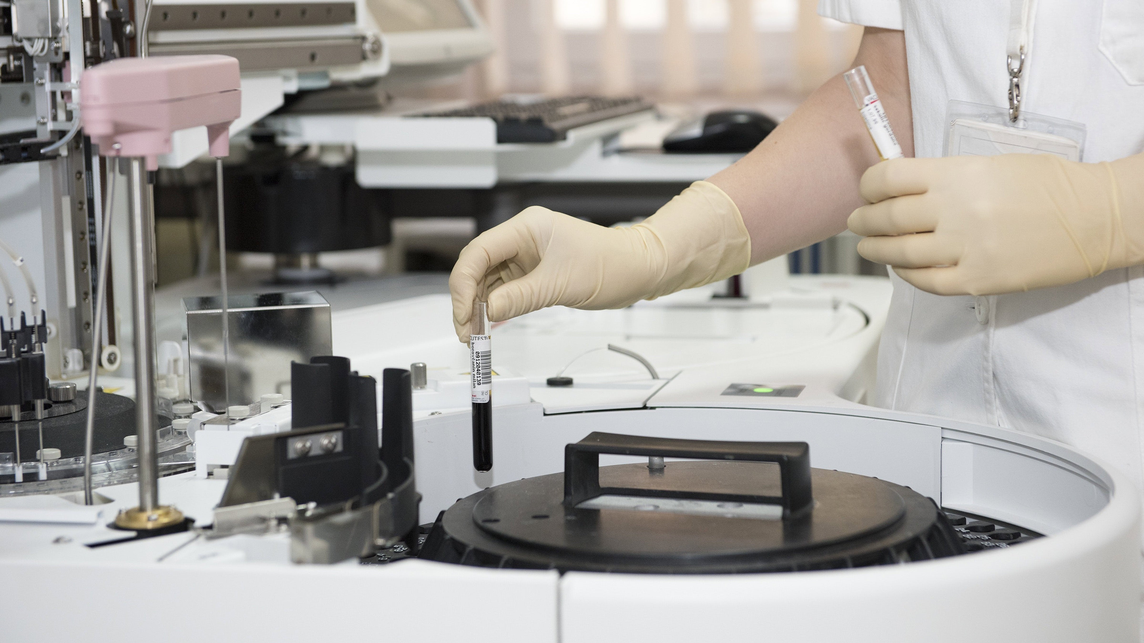 Hand with gloves on putting blood viles into a spinner in a lab