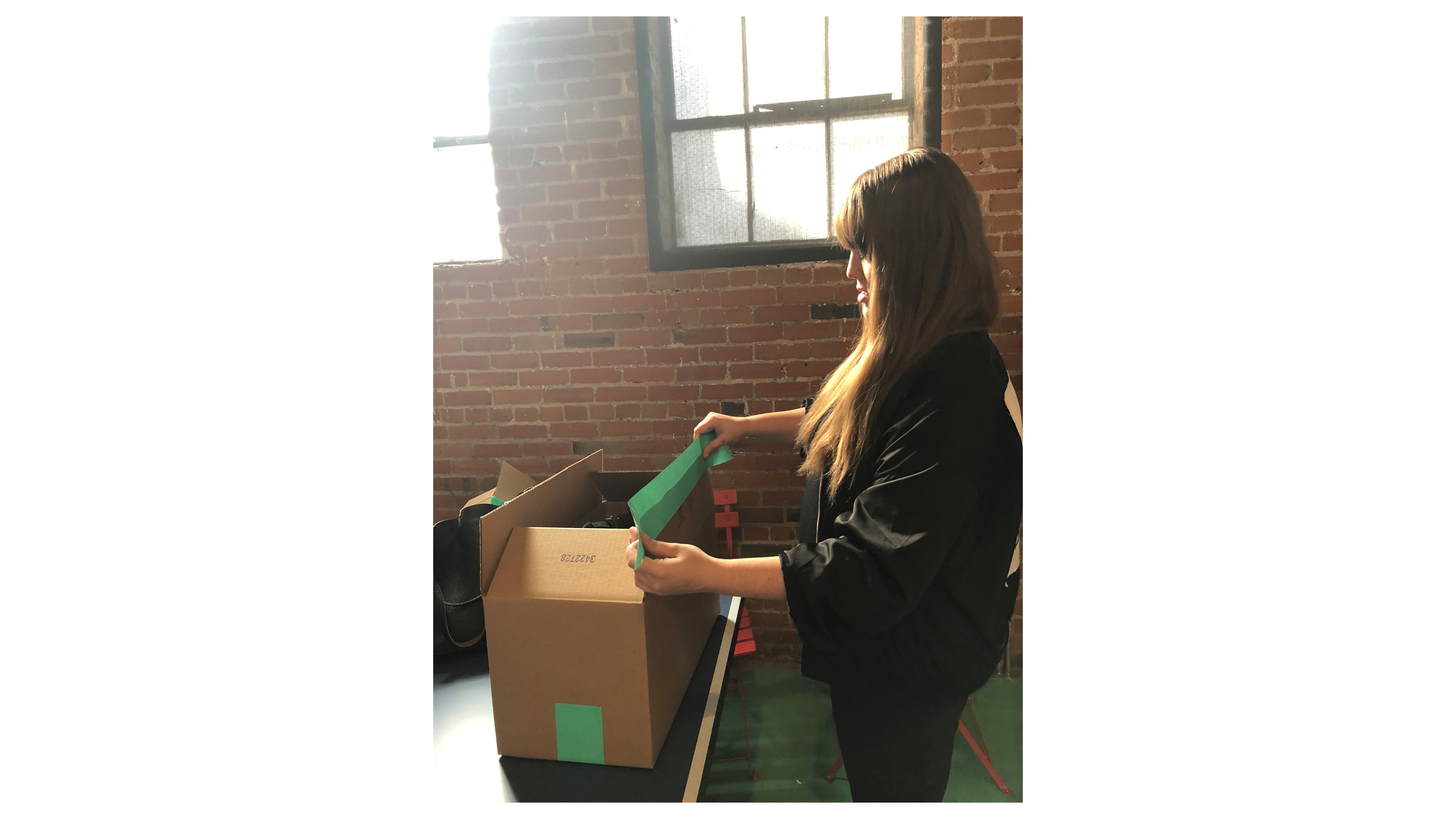 Picture of a Tuft & Needle employee taping up a box