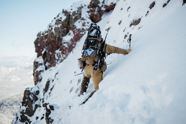 A man balanced on the edge of a snow-covered cliff