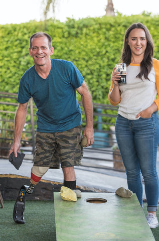 man and woman playing cornhole at a brewery