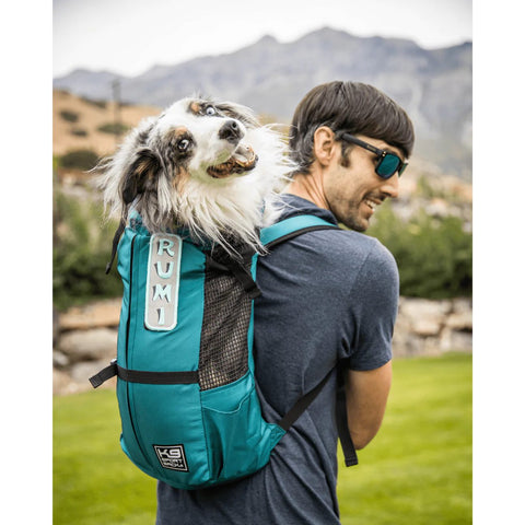 man with an Australian shepherd dog in a dog carrier backpack hiking