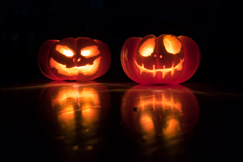 Spooky jack-o-lanterns reflecting on the dark ground.