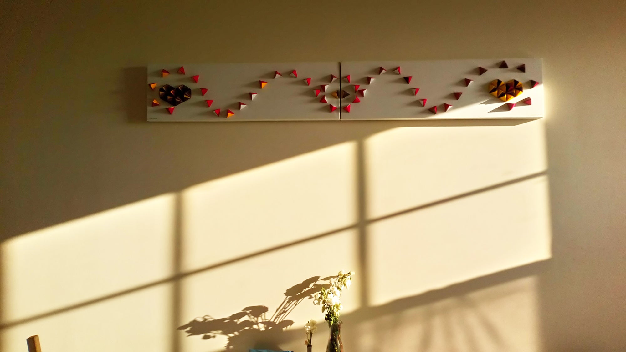 Inspiration, origami artwork by unamarz, on wall with sunlight and shadow of window and flowers