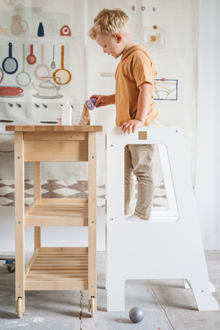 boy standong on white learning tower kitchen helper