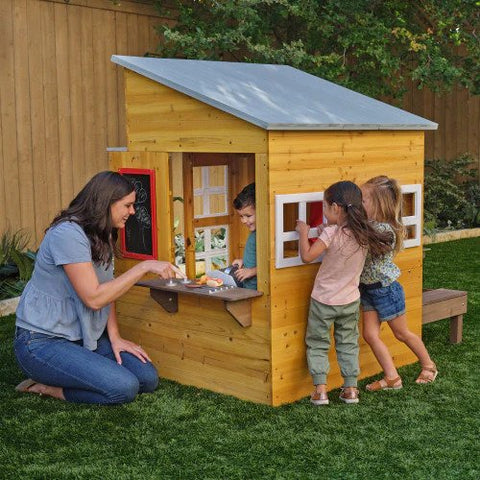 woman and children playing with kidkraft modern outdoor playhouse