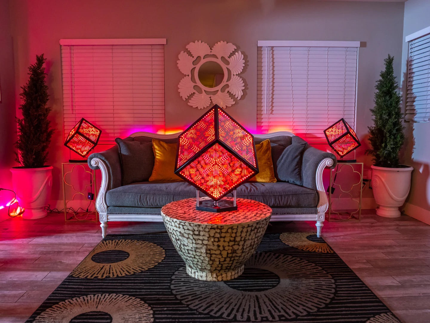 Living room with a couch in the middle of two windows, a circle-patterned rug, and a table with a HyperCube on top of it as a centerpiece decorative lighting ideas