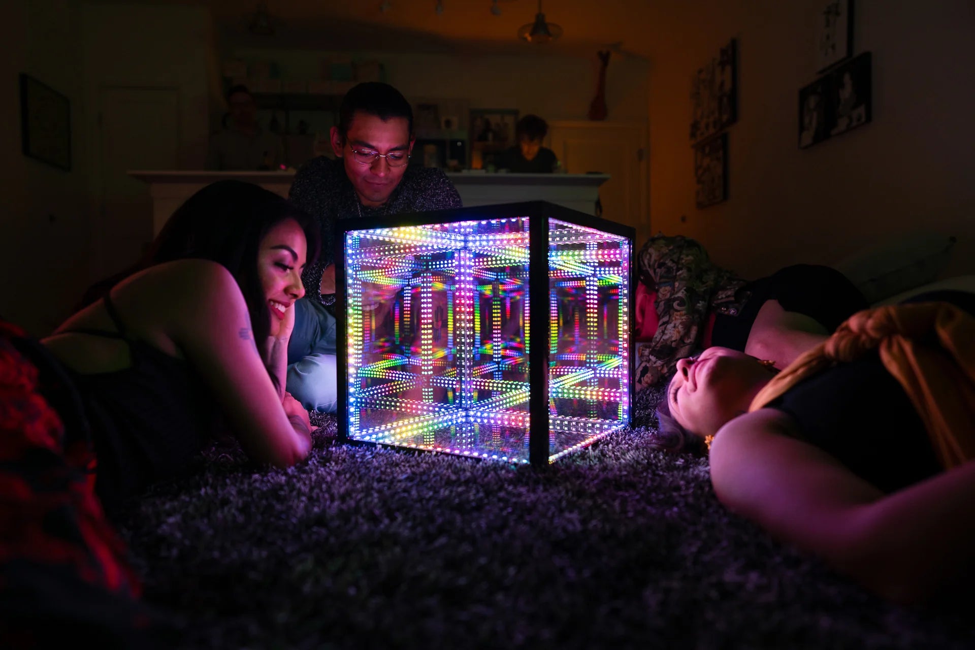 friends laying on bed looking at led cube