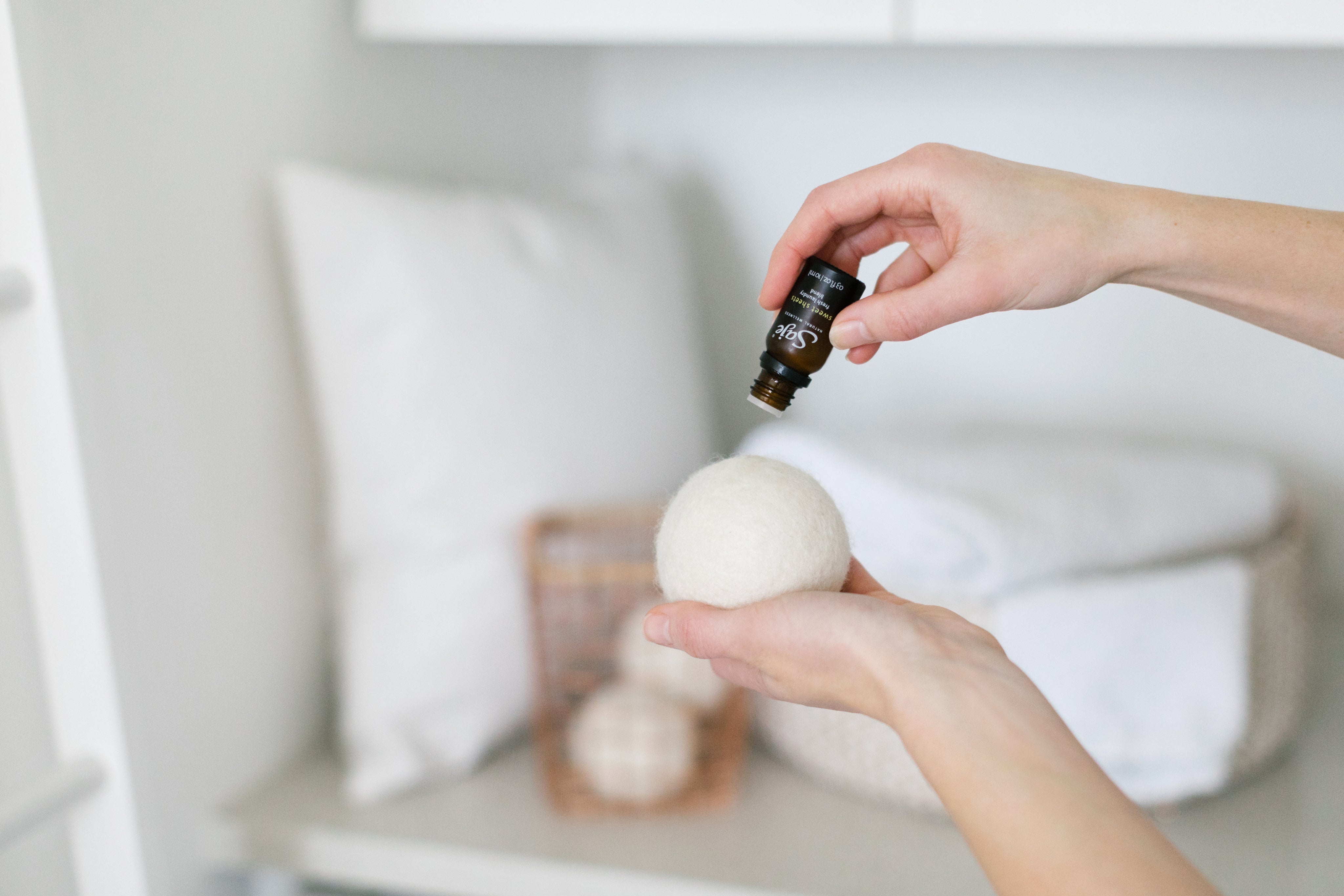 A hand applying diffuser blend drops to a wool laundry ball