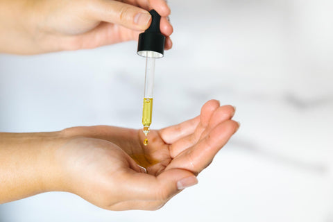 Squeezing dropper of Saje hair repair treatment with rosemary oil into a hand