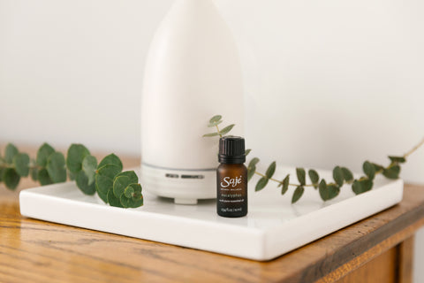 Eucalyptus essential oil bottle and an Aroma Om diffuser on a white tray placed on a wooden nightstand