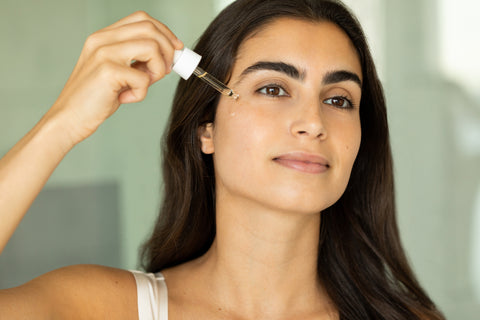 A woman applying glow on face oil to their face