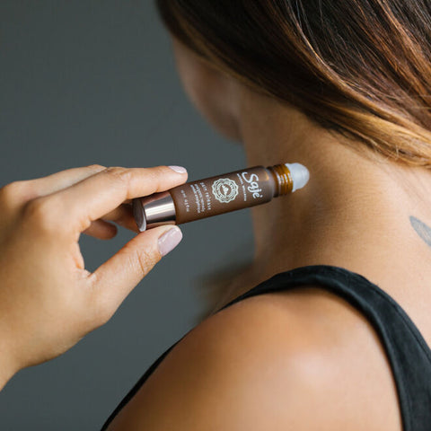 A person applying pain release roll-on to their neck