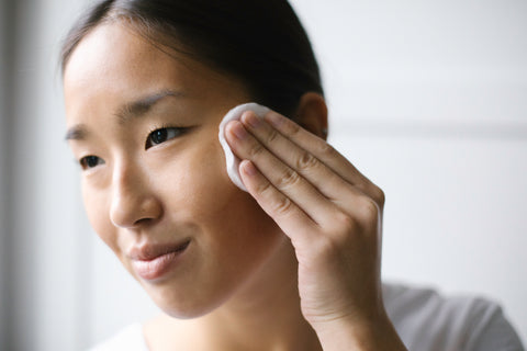 A woman using bare face makeup remover to remove their makeup