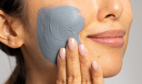 A person applying a clay mask to their face