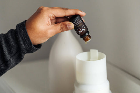 A person adding immune diffuser blend to an essential oil diffuser