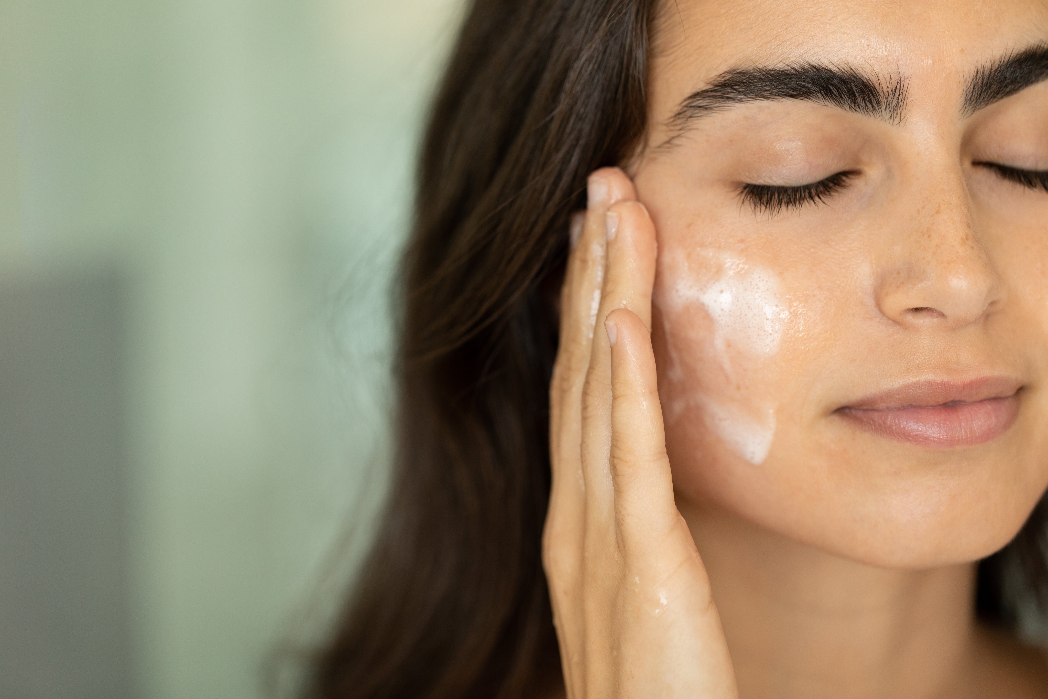 A woman applying Saje moisturizer to her face