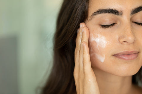 A woman applying moisturizer to their face